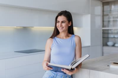 Woman smiling in the kitchen reading a book