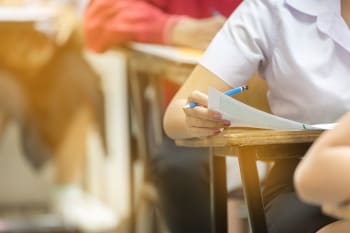 student sitting on row chair doing final exam in classroom