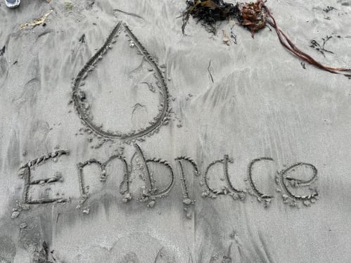 The word Embrace wrote in the sand