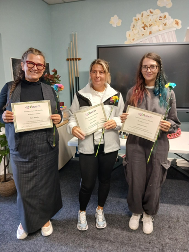 Three parents proudly displaying their certificates of completion at the final Extern parent programme session.